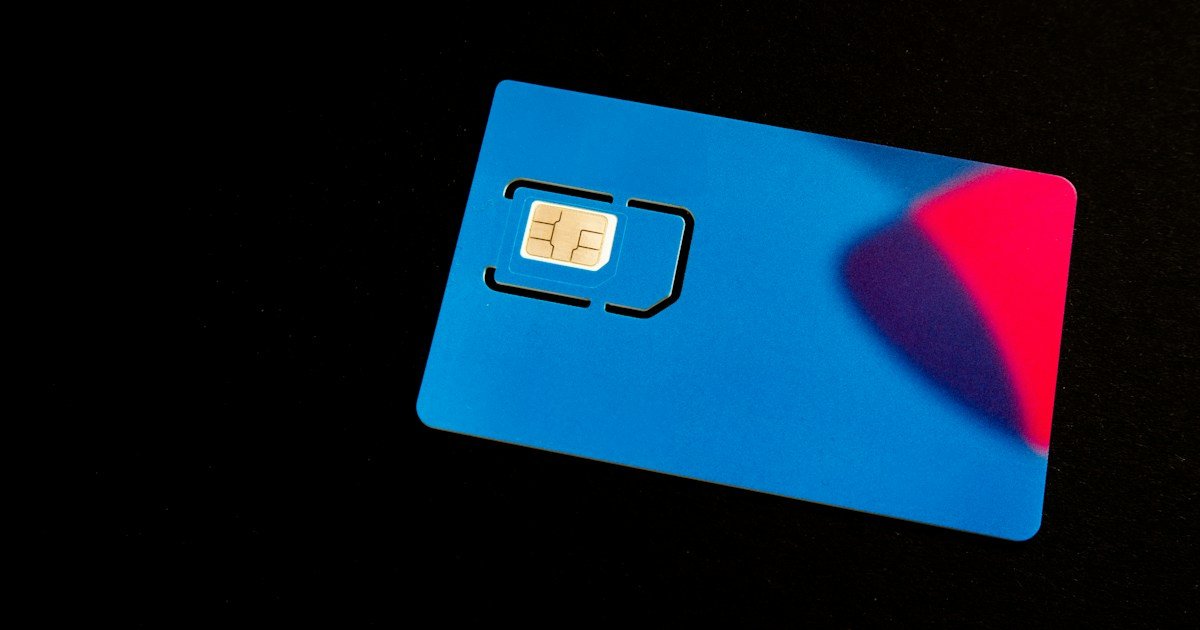 Blue physical SIM card on a dark surface, used to illustrate travel connectivity options