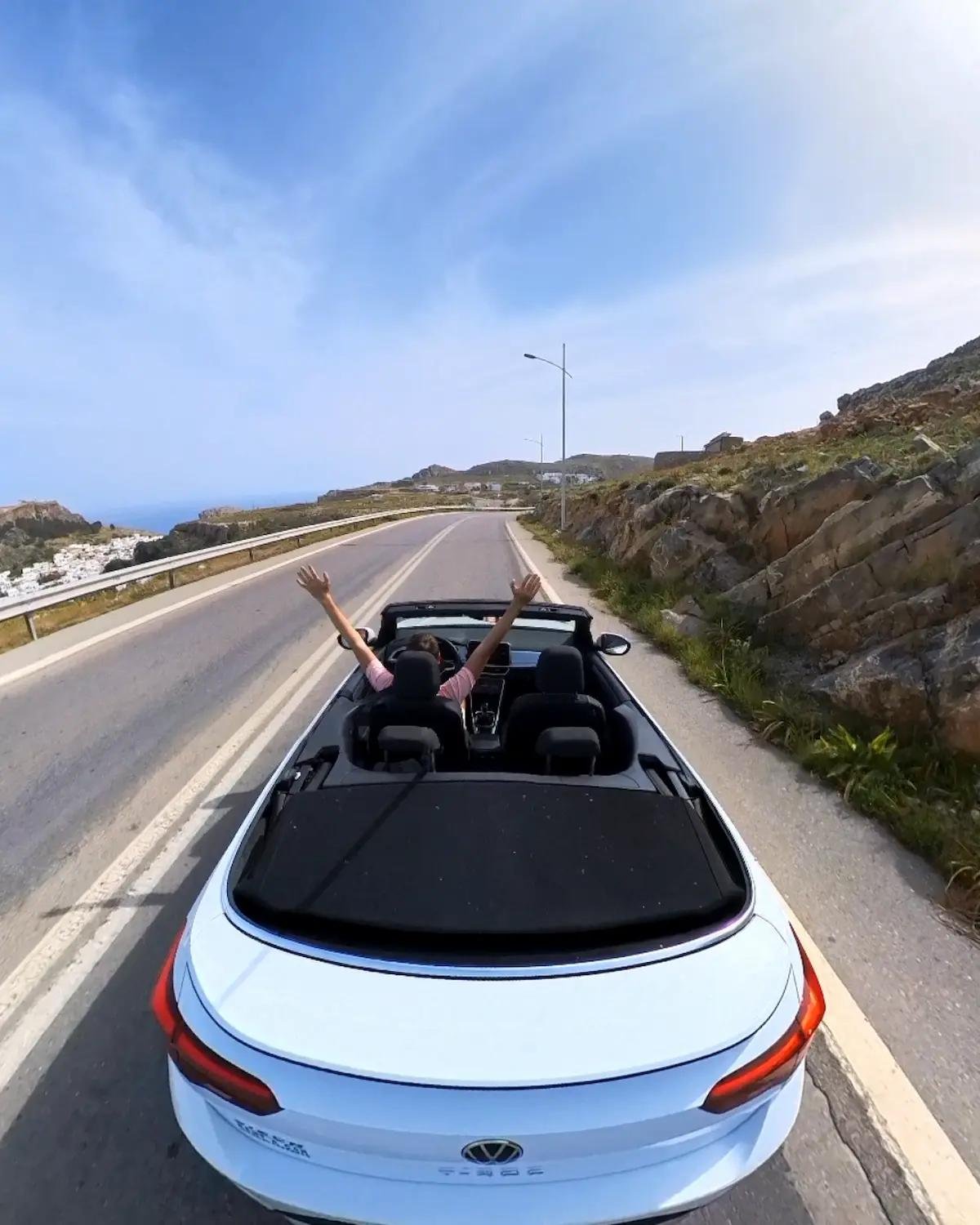 Open-top rental car on a coastal road above Lindos, Rhodes, photographed by Looneytravels.