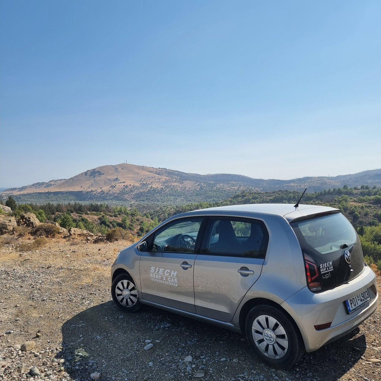 Silver rental car parked at a mountain viewpoint in inland Rhodes, photographed by Looneytravels.